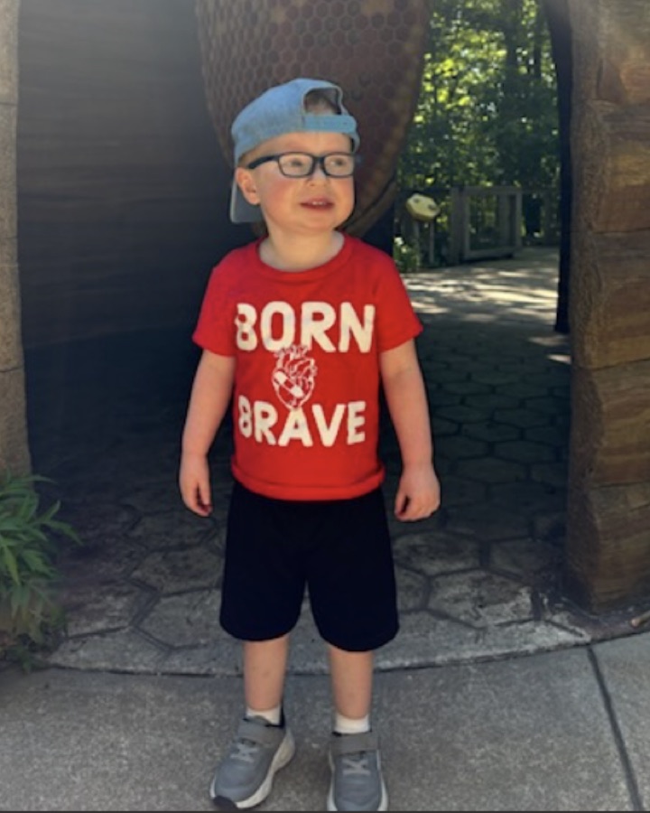 Carter, age 4, smiling in a red Born Brave t-shirt
